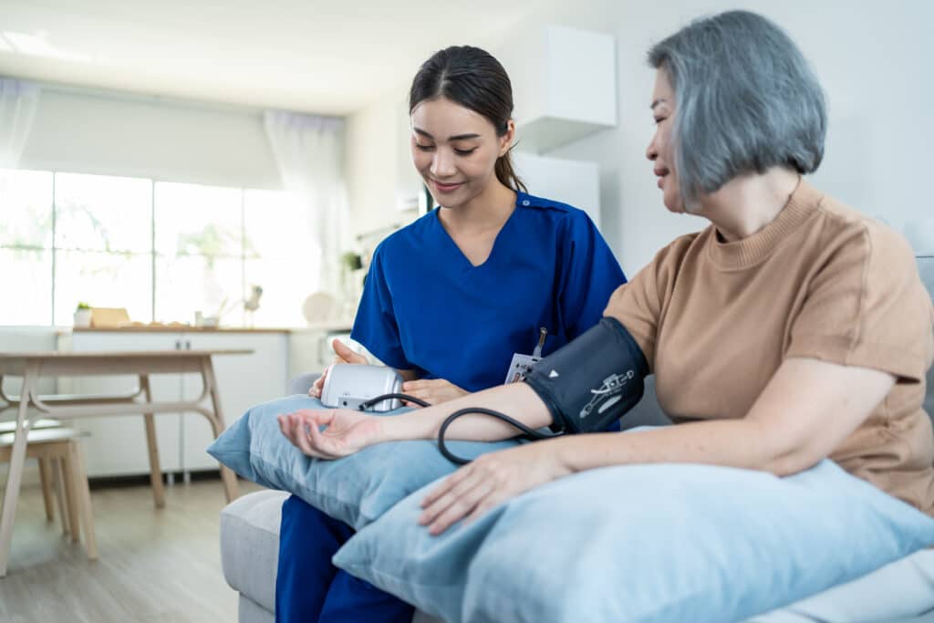Asian caregiver doctor examine older patient use blood pressure gauge at nursing home